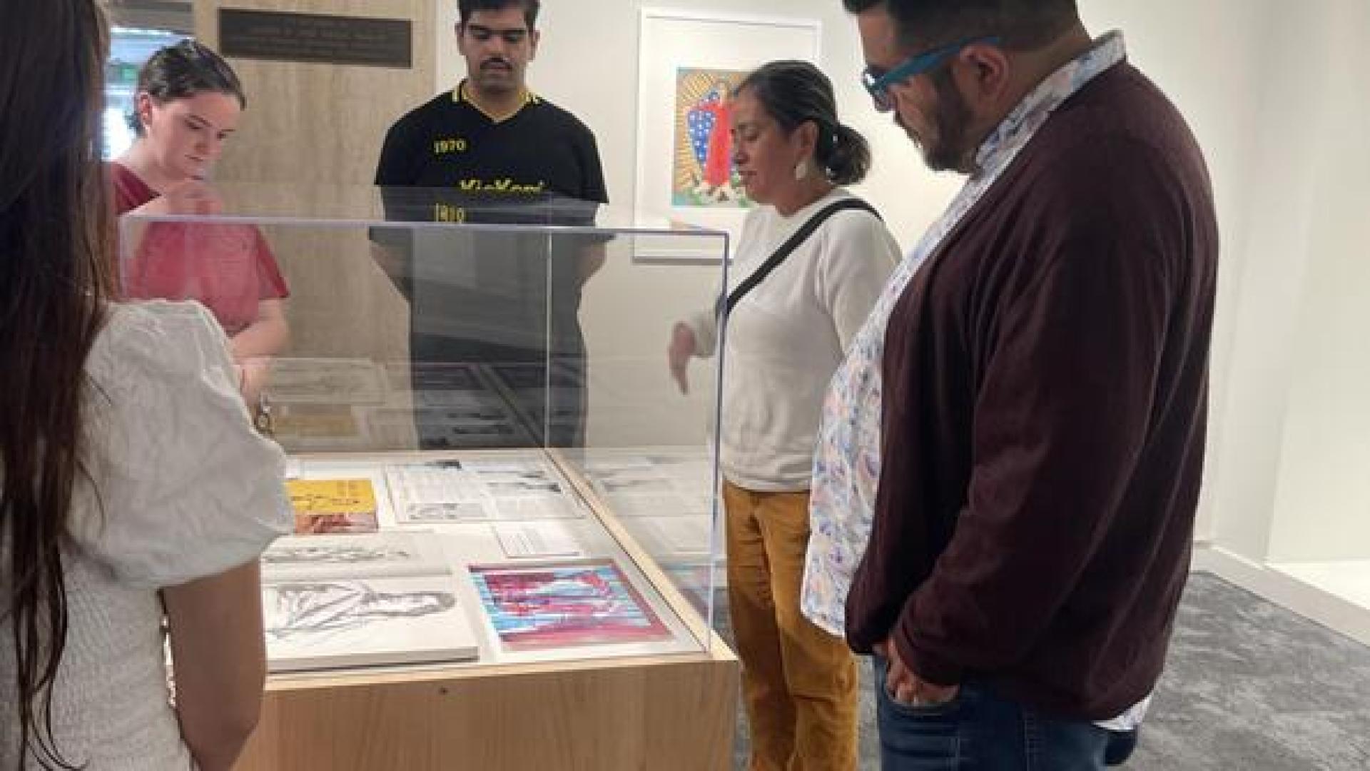 People gathered around a case of artworks
