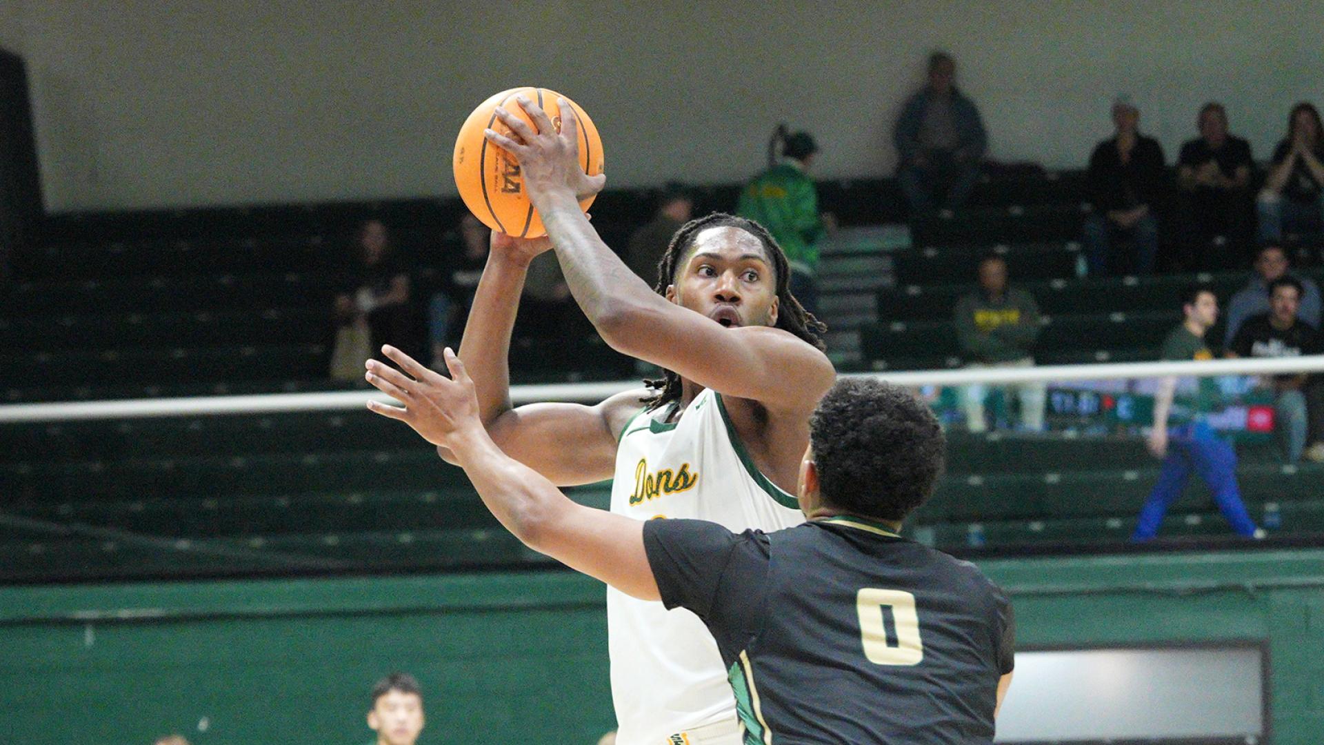 student jumps with basketball in the air