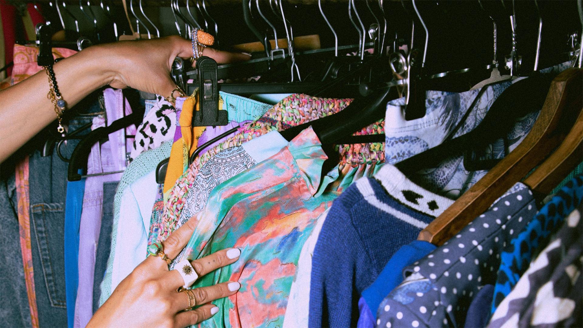 Someone looking through clothes on clothing rack