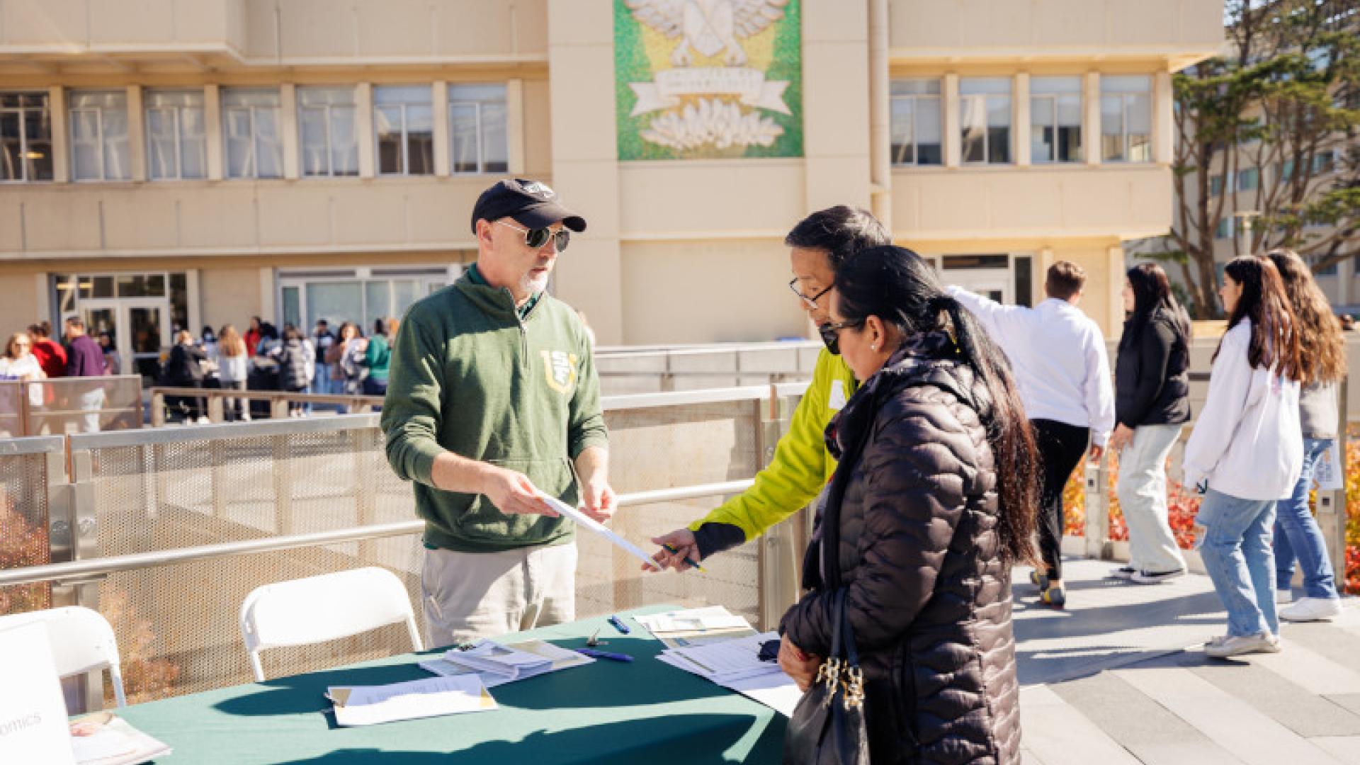 Two students speaking with a representative at a tabling event
