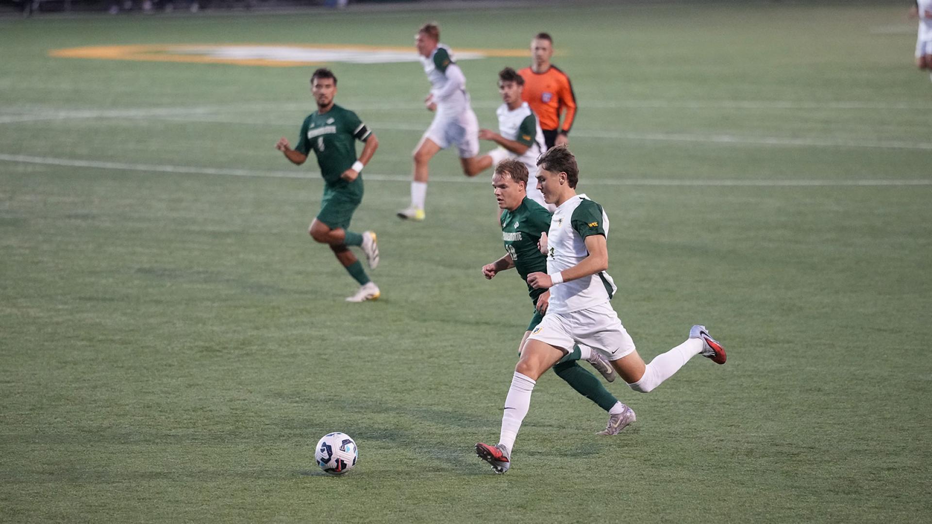 soccer players run after ball during game