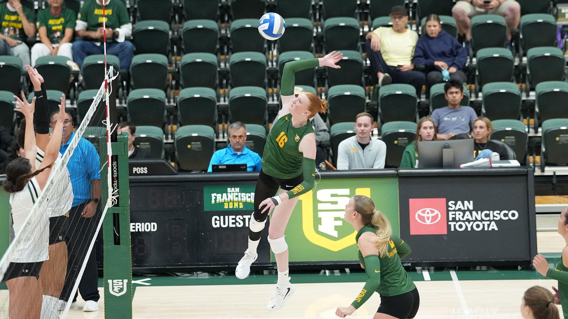 student athlete hits volleyball over net