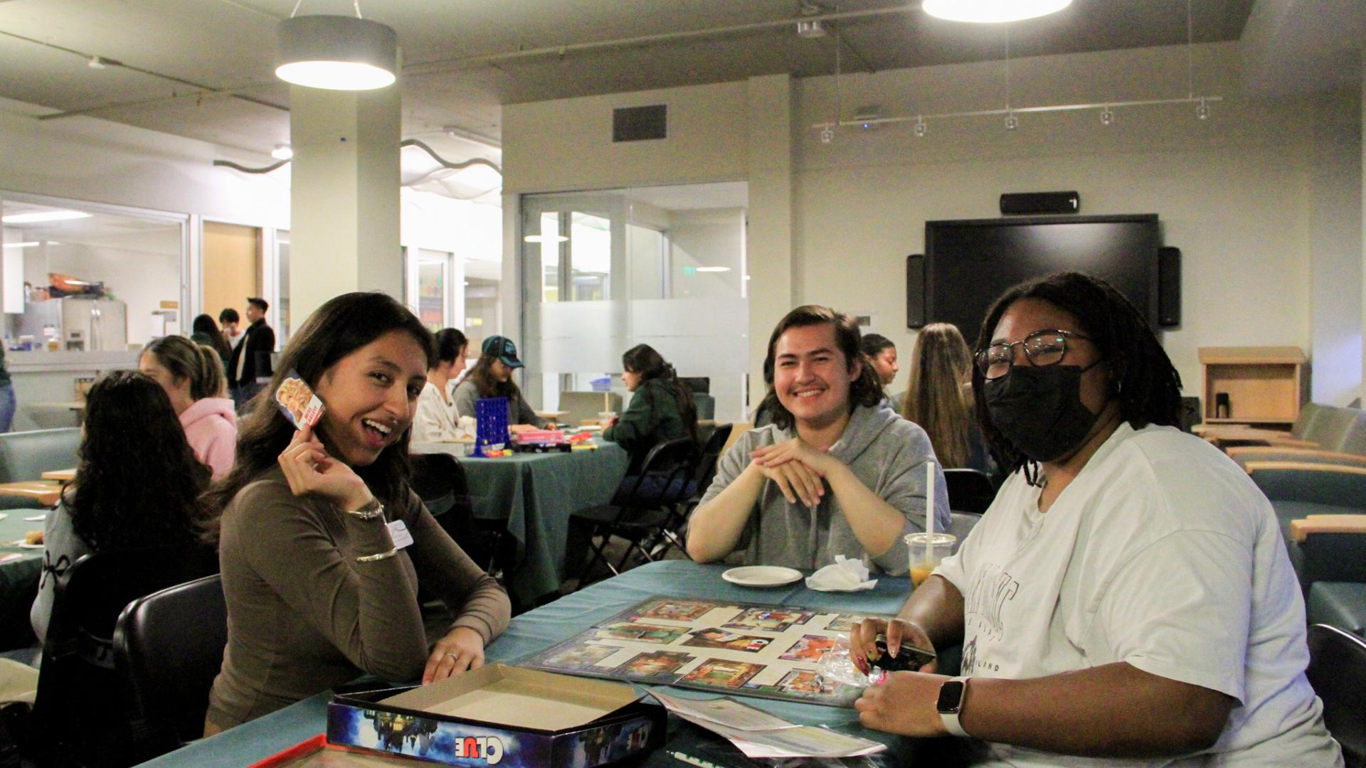 Three people sitting at a table playing board games