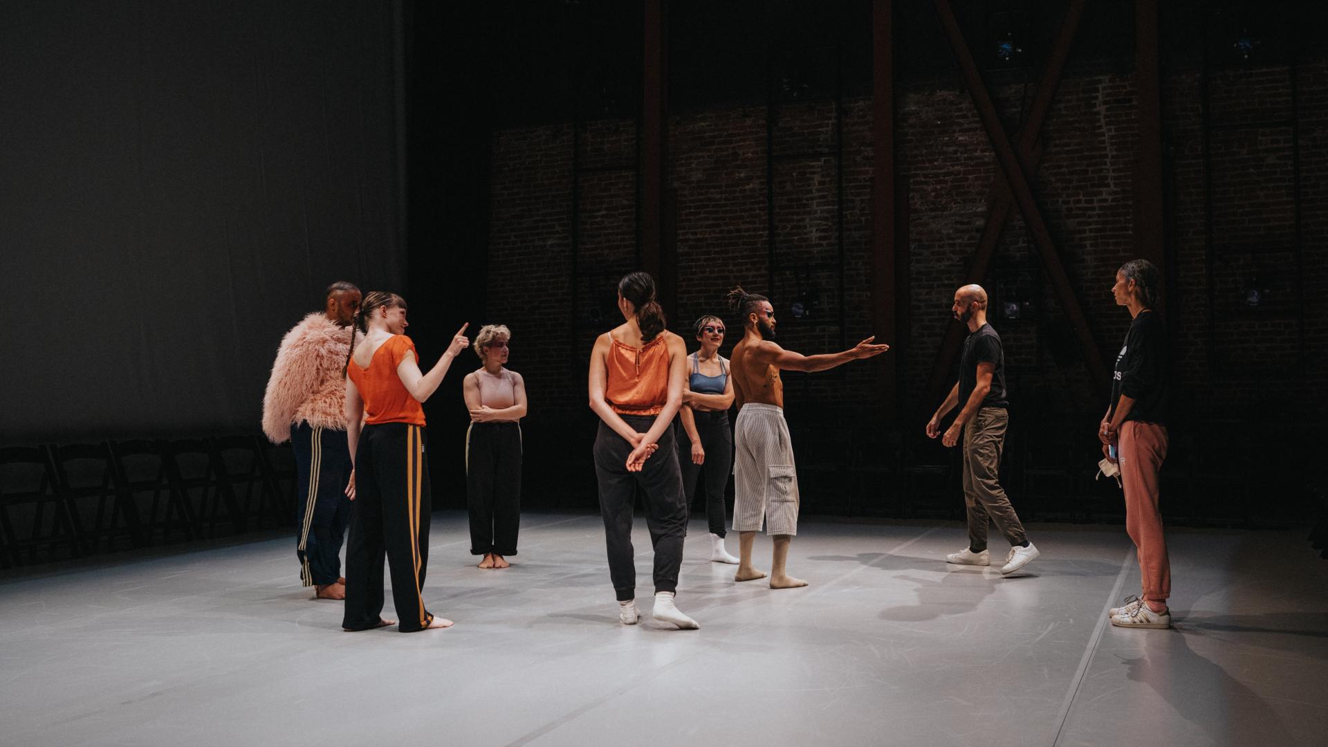performers listening to choreographer in rehearsal