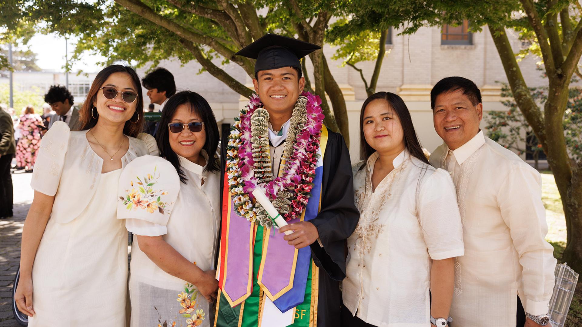 student poses with his family during commencement