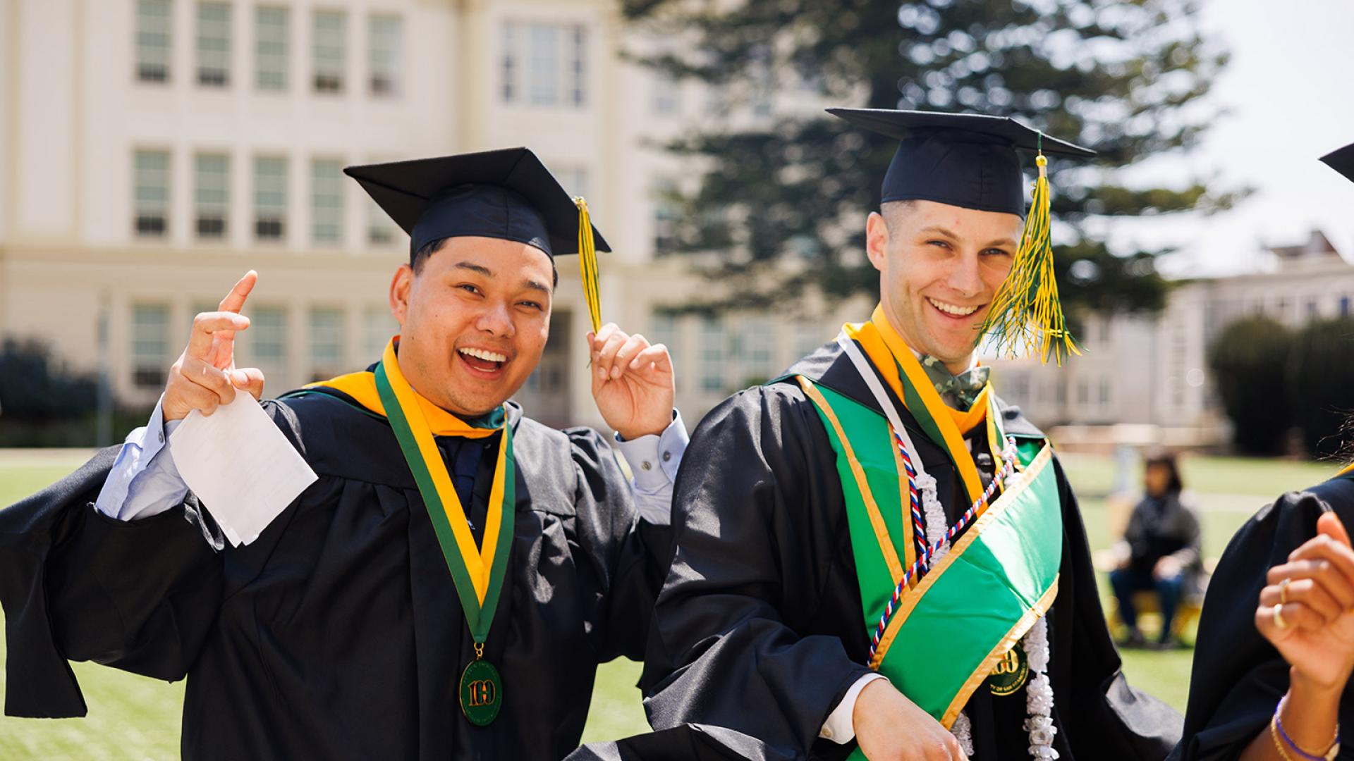 two students smiling in their caps and gowns on usf campus
