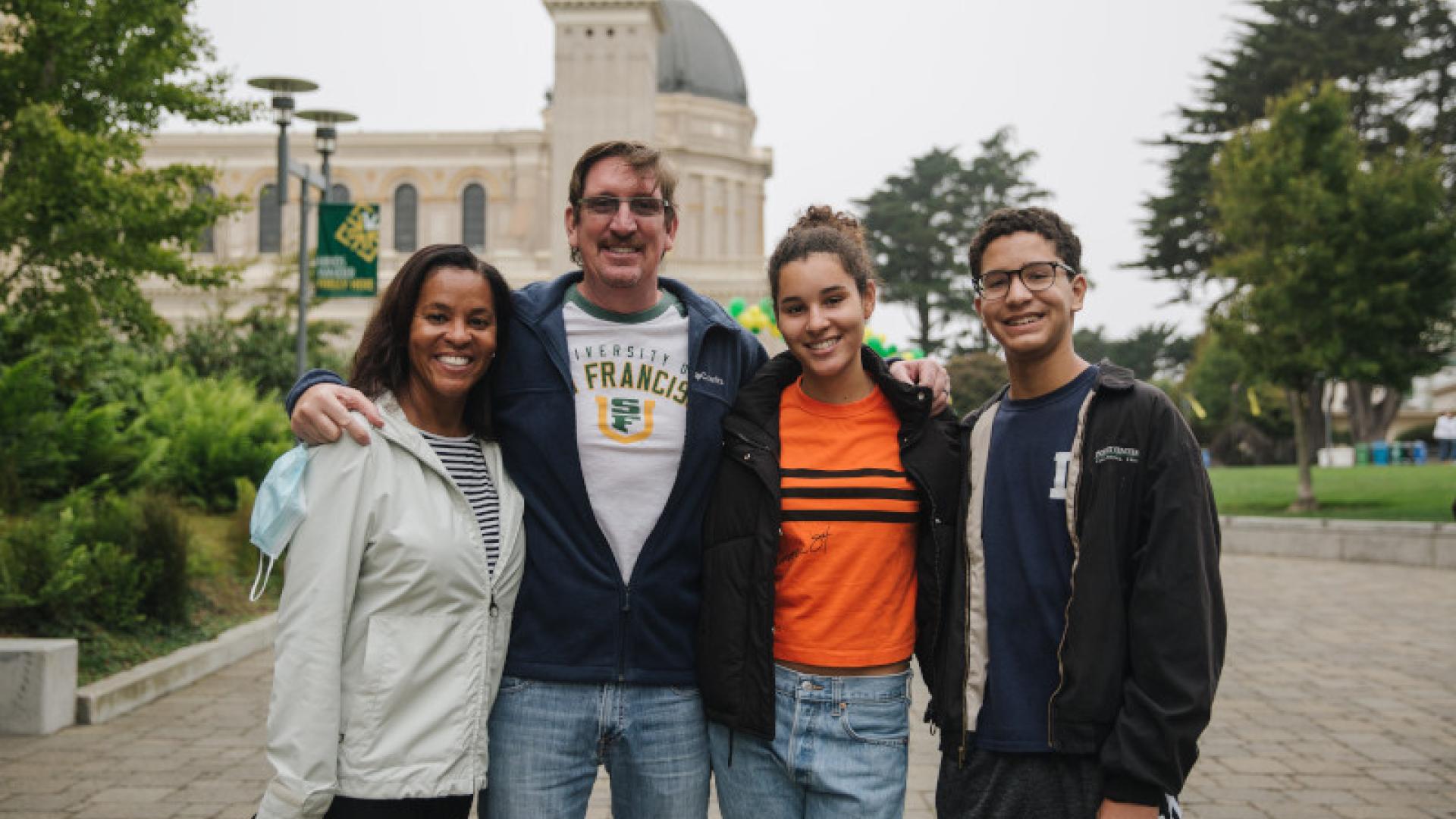 Four family members smiling and church is in the background.