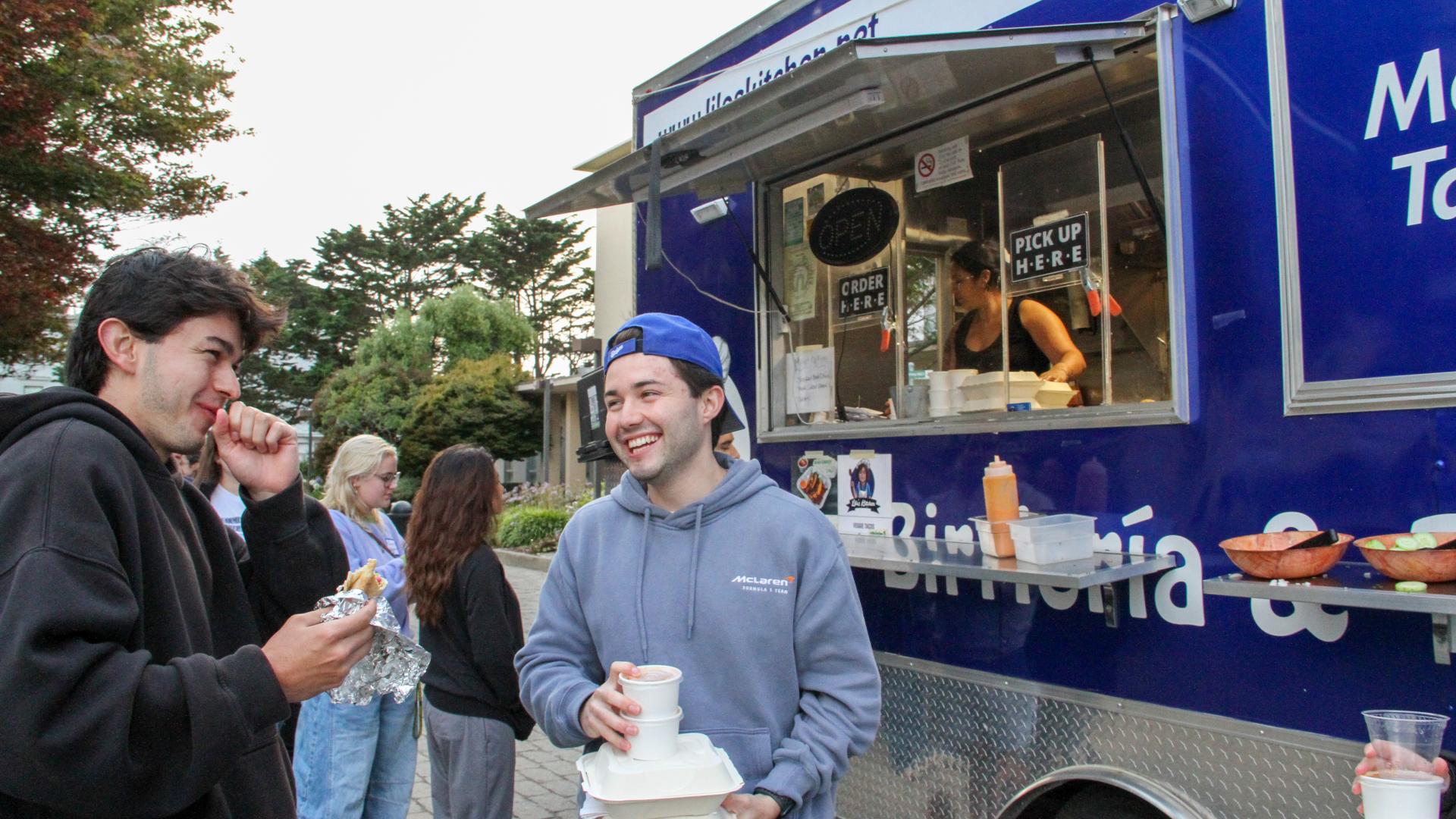 Two students smiling while getting their food from the food truck