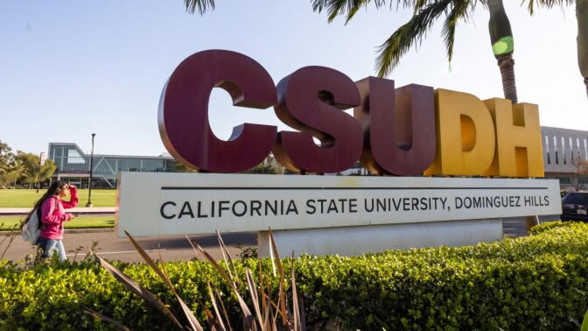 Sign of CSUDH and a student walking by 