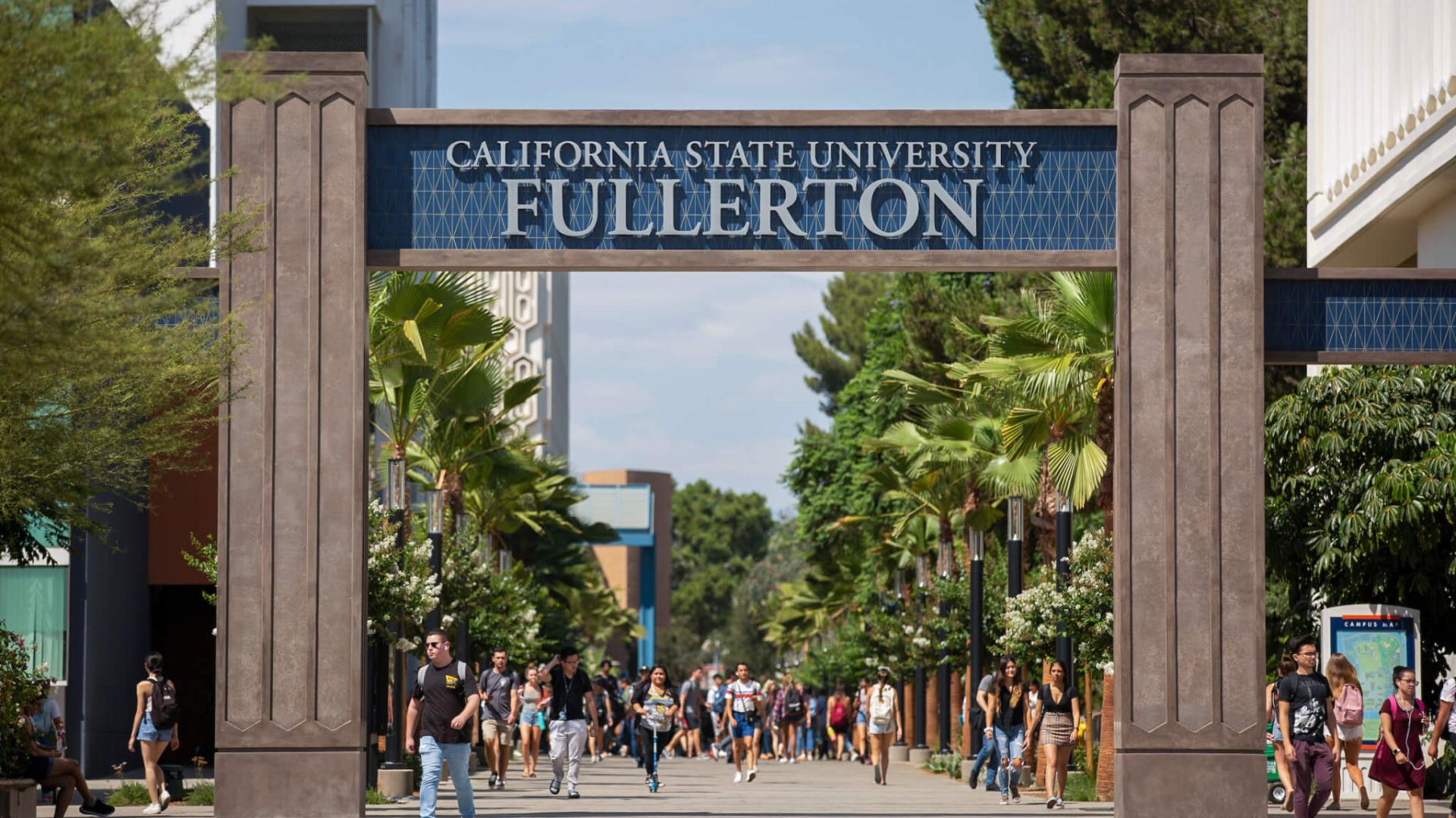 Sign that read the name of the university and students walking beneath it 