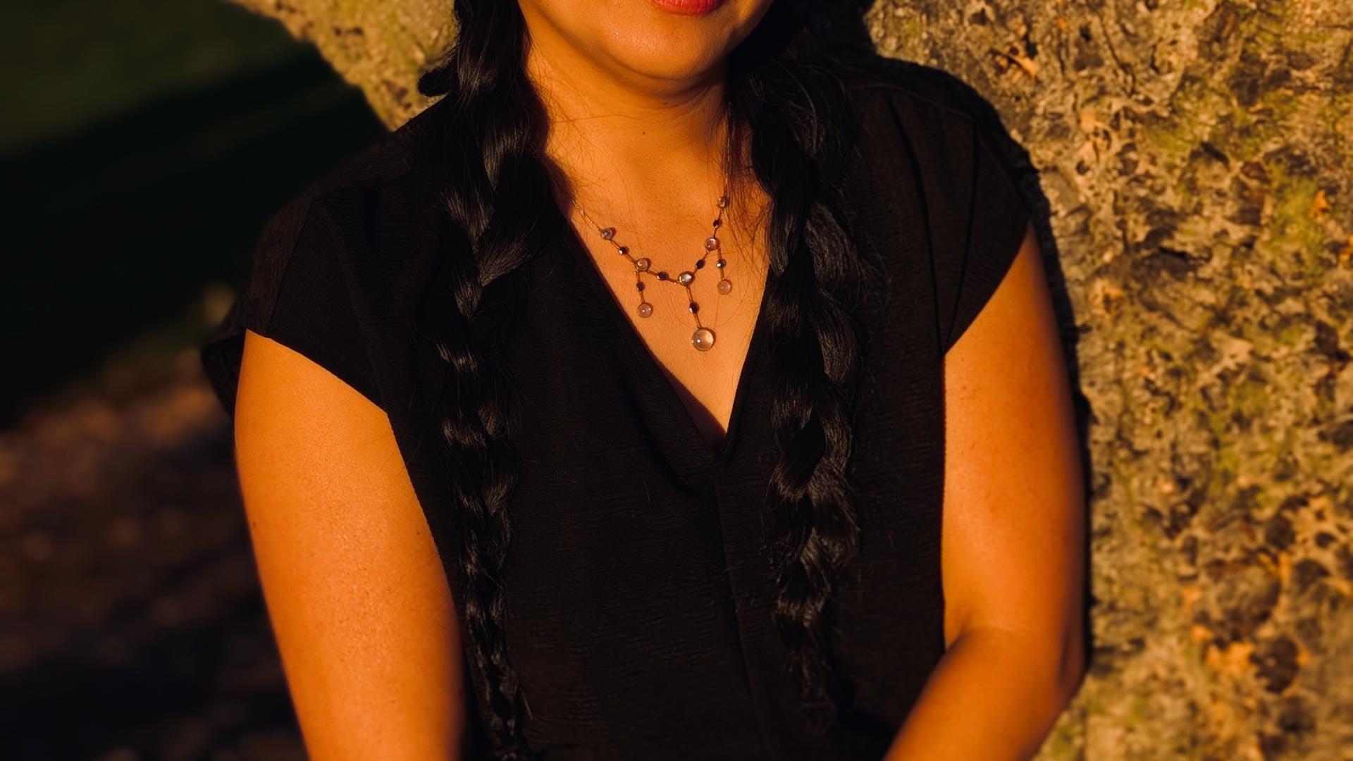 Vanessa standing with her arms crossed in front of a rock 