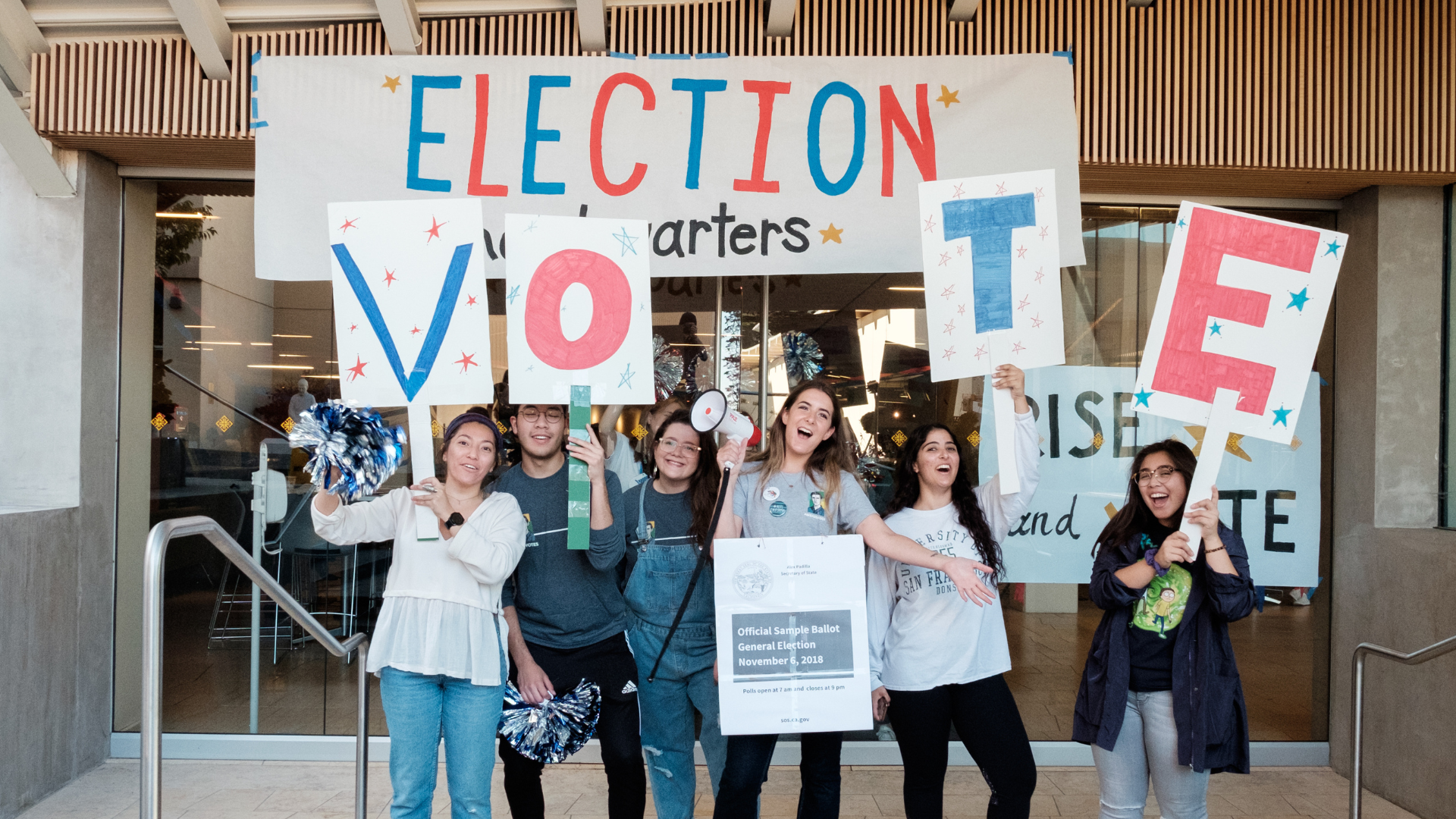 students stand in front of an Election banner holding letters VOTE 