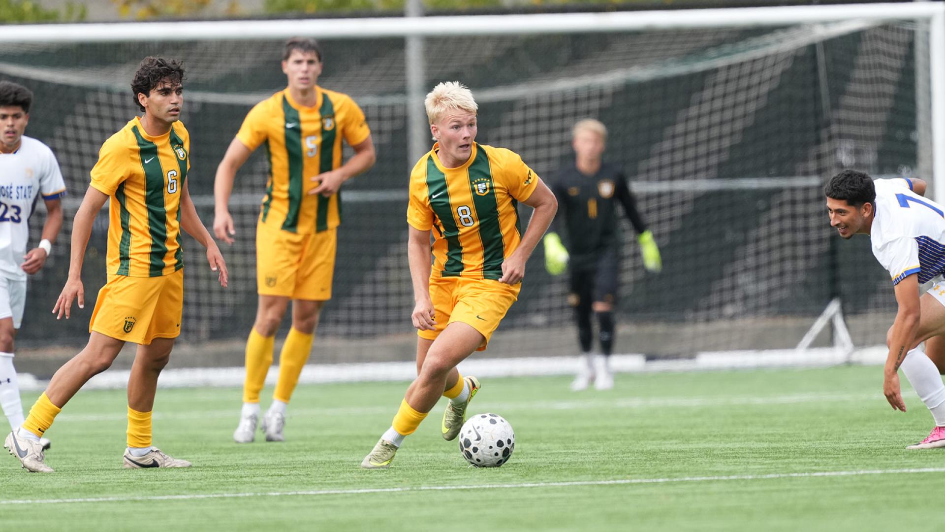 student runs with soccer ball during a game